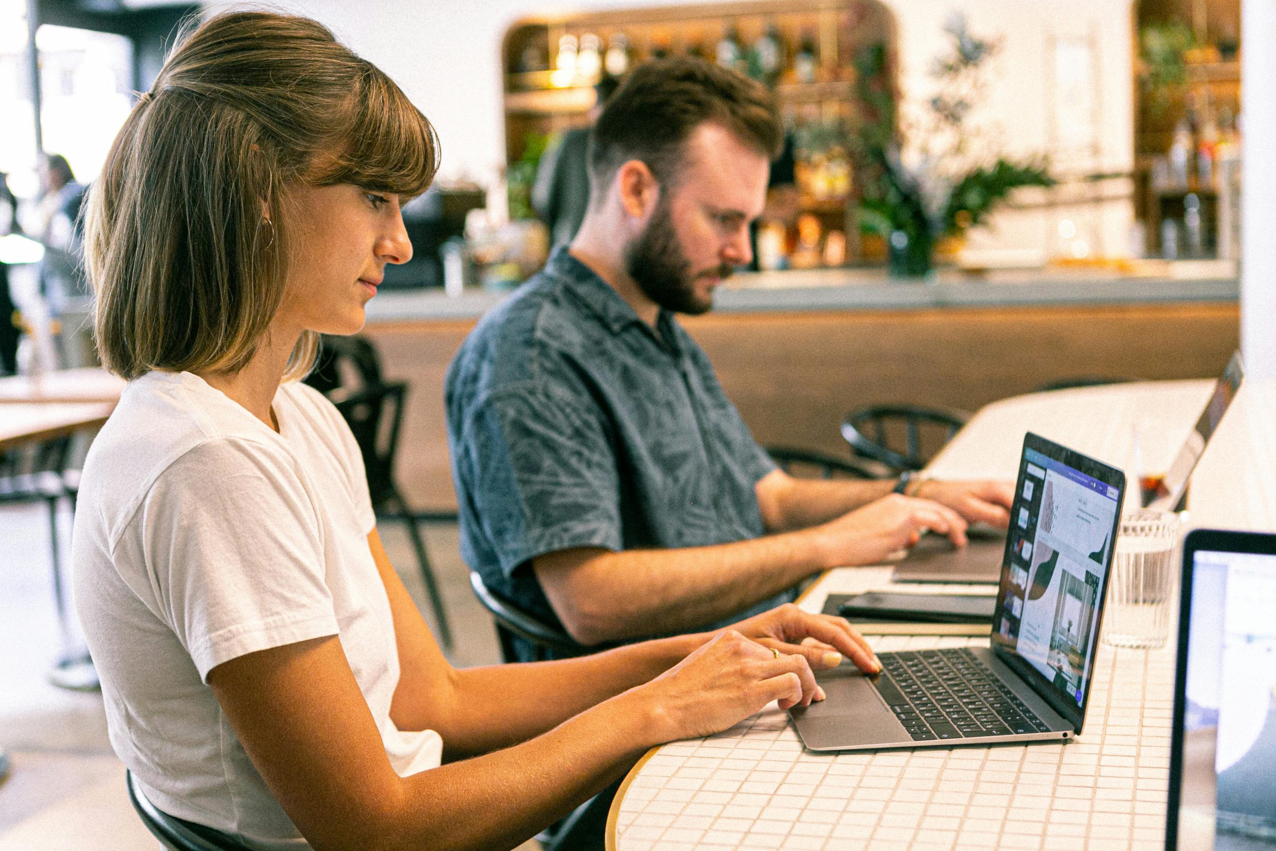 a man and woman sitting at a table using a laptop