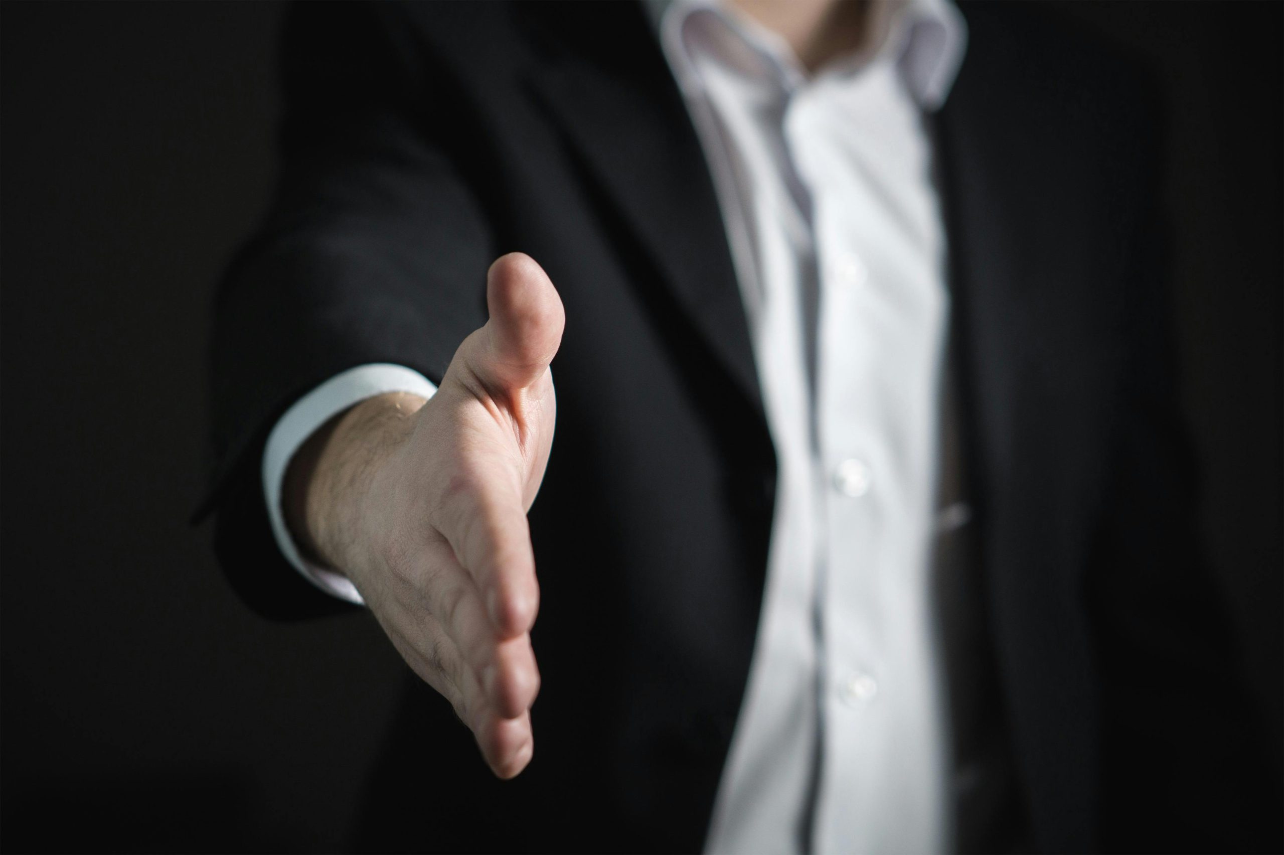 a man in a suit reaching out to shake hand
